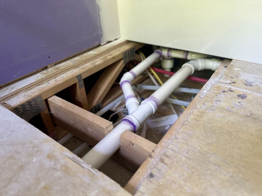 Exposed PVC plumbing pipes under a floor opening during home repiping work